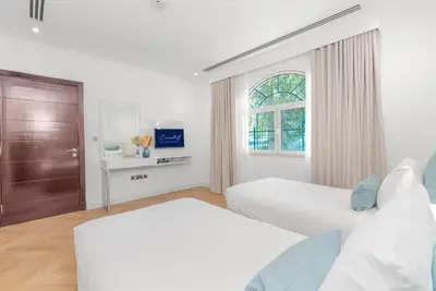 a white bedroom with two beds and a window at Private villa in Dubai with swimming pool and huge garden in Dubai