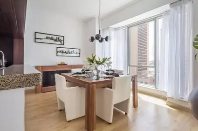 a kitchen with a wooden table and white chairs at Frank Porter - Beauport in Dubai