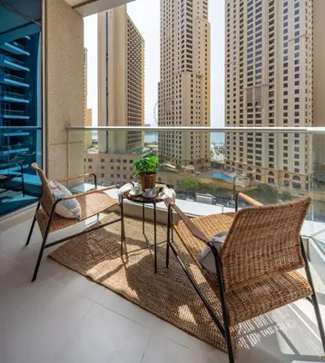 a balcony with chairs and a table and a view of a city at Frank Porter - Beauport in Dubai