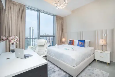 a bedroom with a bed and a desk with a laptop at Luxurious 3BR Apartment with Panoramic Marina View in Dubai