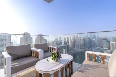 a balcony with two chairs and a table and a city at Luxurious 3BR Apartment with Panoramic Marina View in Dubai