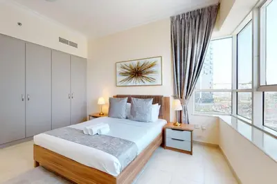 a bedroom with a bed and a large window at V3 Tower - Elegant One Bedroom in Dubai
