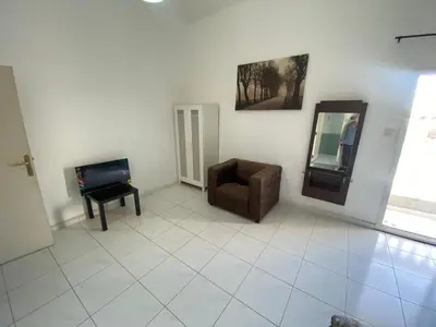 a living room with a chair and a mirror at Nice Rooms for Rent in Compound Housing near Burj Alarab Dubai Villa 125 in Dubai