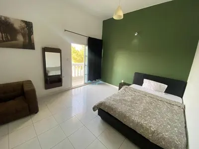 a bedroom with a bed and a green wall at Nice Rooms for Rent in Compound Housing near Burj Alarab Dubai Villa 125 in Dubai