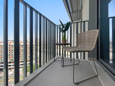a chair on a balcony with a view of a city at Silkhaus modern 1BDR in Belgravia Heights with pool & gym in Dubai