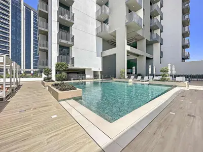 a swimming pool in front of a building at Silkhaus modern 1BDR in Belgravia Heights with pool & gym in Dubai