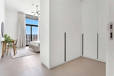 a white room with white cabinets and a bedroom at Silkhaus modern 1BDR in Belgravia Heights with pool & gym in Dubai