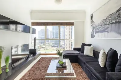 a living room with a black couch and a large window at Frank Porter - MAG214 in Dubai