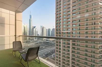 a balcony with two chairs and a view of a city at Silkhaus chic 1BDR in west avenue with Pool & gym access in Dubai