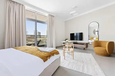 a bedroom with a bed and a desk and a television at Silkhaus spacious studio in Art Gardens with gym & pool access in Dubai
