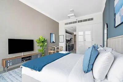 a bedroom with a large bed and a flat screen tv at Silkhaus new studio in Art Gardens pool access in Dubai