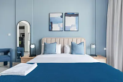 a blue bedroom with a large bed with blue walls at Silkhaus new studio in Art Gardens pool access in Dubai