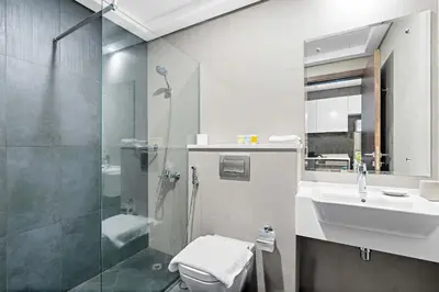 a bathroom with a shower toilet and a sink at Silkhaus new studio in Art Gardens pool access in Dubai