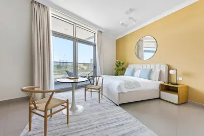 a bedroom with a bed and a table and a window at Silkhaus new studio in Art Gardens gym & pool access in Dubai