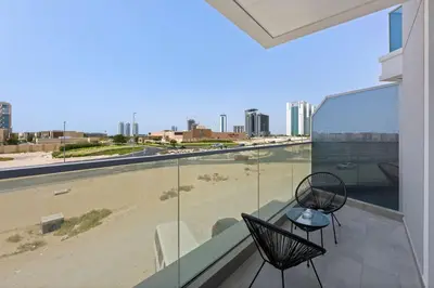 a balcony with two chairs and a view of a beach at Silkhaus new studio in Art Gardens gym & pool access in Dubai