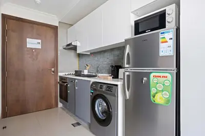 a kitchen with a stainless steel refrigerator and a dishwasher at Silkhaus new studio in Art Gardens gym & pool access in Dubai