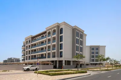 a large white building with a car parked in front of it at Silkhaus exquisite studio in Art Gardens with gym access in Dubai