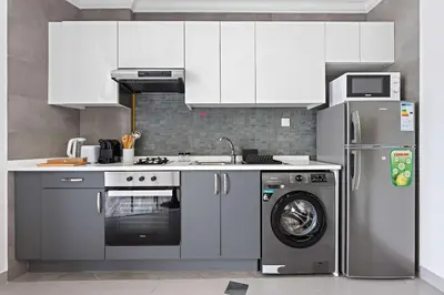 a kitchen with white cabinets and a washing machine at Silkhaus Modern Studio with New Furniture in Dubai