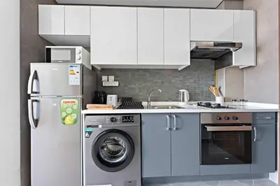 a kitchen with a refrigerator and a washing machine at Silkhaus Chic Studio in Art Gardens Modern Living in Dubai