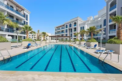 a swimming pool with lounge chairs and a building at Silkhaus Chic Studio in Art Gardens Modern Living in Dubai