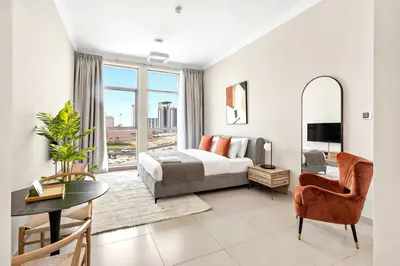 a bedroom with a bed and a table and a chair at Silkhaus furnished studio in Art Gardens with pool access in Dubai