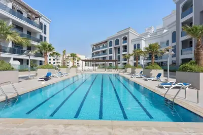 a swimming pool with lounge chairs and a building at Silkhaus furnished studio in Art Gardens with pool access in Dubai