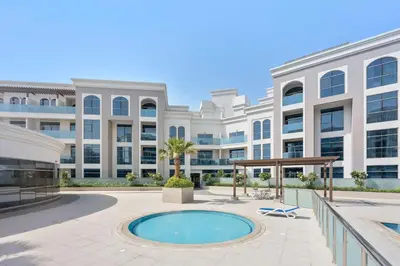 an exterior view of a large building with a pool at Silkhaus furnished studio in Art Gardens with pool access in Dubai