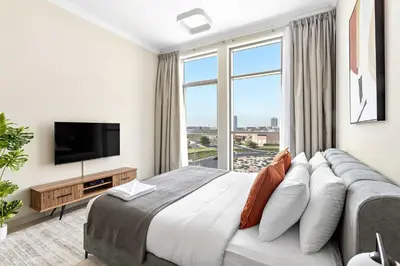 a bedroom with a large bed and a large window at Silkhaus furnished studio in Art Gardens with pool access in Dubai
