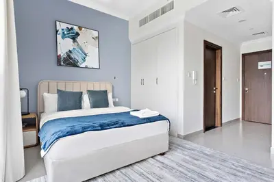 a bedroom with a large bed with a blue blanket at Silkhaus luxurious studio in Art Gardens with gym access in Dubai