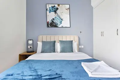 a blue bedroom with a bed with a blue blanket at Silkhaus luxurious studio in Art Gardens with gym access in Dubai