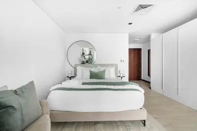 a white bedroom with a large bed and a couch at Silkhaus modern studio in Liberty House in Dubai
