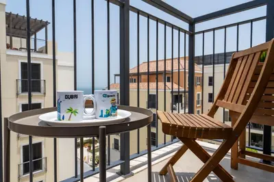 a table with two mugs and a chair on a balcony at HiGuests - Stylish Waterfront Retreat With Balcony in La Mer in Dubai