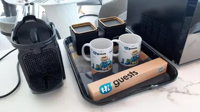 a desk with coffee cups and a laptop computer at HiGuests - Stylish Waterfront Retreat With Balcony in La Mer in Dubai