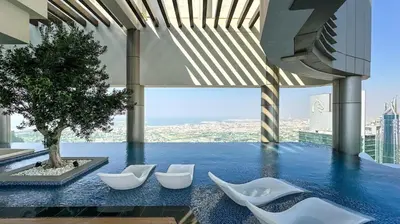 a pool with white chairs and a tree on a building at Stunning 2BR with Burj Views Infinity Pool in Dubai