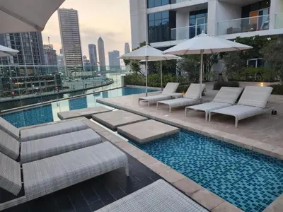 a pool with lounge chairs and umbrellas on a building at White Sage - Fancy Studio With Mesmerizing Canal Views in Dubai