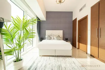 a bedroom with a white bed and a plant at Everluxe Lovely Studio Apt In Business Bay in Dubai