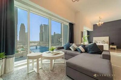 a living room with a couch and a large window at Everluxe Lovely Studio Apt In Business Bay in Dubai