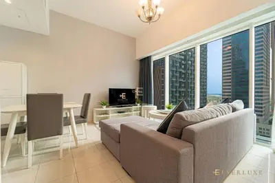 a living room with a couch and a table with a television at Everluxe Lovely Studio Apt In Business Bay in Dubai