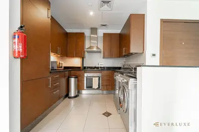 a large kitchen with wooden cabinets and a dishwasher at Everluxe Lovely Studio Apt In Business Bay in Dubai