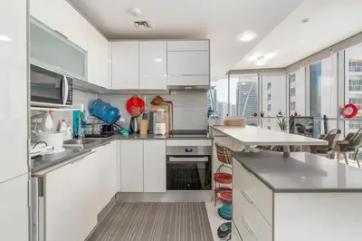 a kitchen with white cabinets and a large window at Summer Deal! Stylish 1 BR in Jumeirah Lake Towers in Dubai