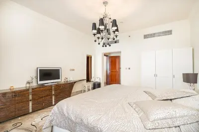 a white bedroom with a bed and a tv at Daniels Sea View 2BR in Fairmont The Palm in Dubai