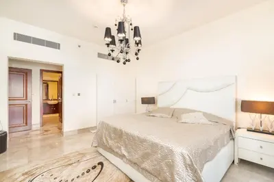 a white bedroom with a large bed and a chandelier at Daniels Sea View 2BR in Fairmont The Palm in Dubai