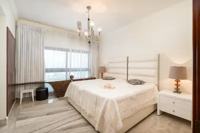 a white bedroom with a large bed and a window at Daniels Sea View 2BR in Fairmont The Palm in Dubai