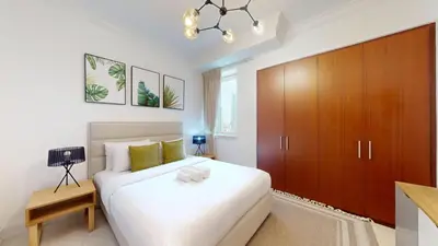 a bedroom with a white bed and a wooden cabinet at Al Murjan - Appealing Two Bedroom in Dubai