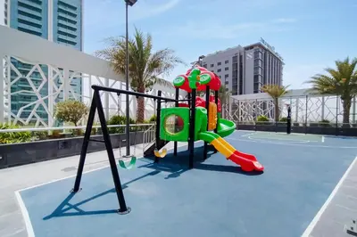a playground on a tennis court with buildings at Modern Studio with Pool & Gym Access in Dubai