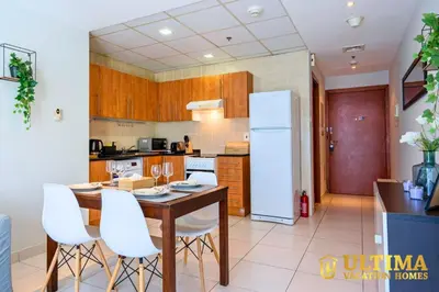 a kitchen with a wooden table and white appliances at Alluring 1BR Opp to JBR Beach- Marina Views in Dubai