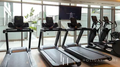 a gym with three treadmills in front of a window at LUX The Executive Sobha Suite 2 in Dubai