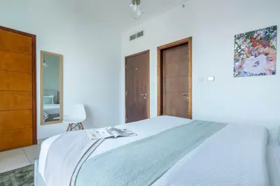 a white bedroom with a bed and wooden cabinets at Frank Porter - South Ridge 6 in Dubai