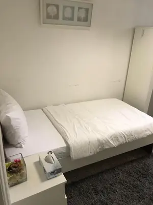 a bedroom with a bed with white sheets and a table at Relaxing Private Rooms in Compound Housing near Burj Alarab Villa 124 in Dubai