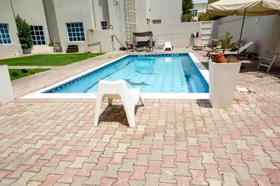 a swimming pool with a white chair sitting next to it at Relaxing Private Rooms in Compound Housing near Burj Alarab Villa 124 in Dubai